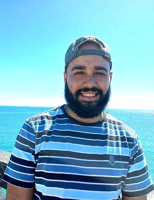 Portrait of Justin Booysen, smiling with a cap on and a glorious beard